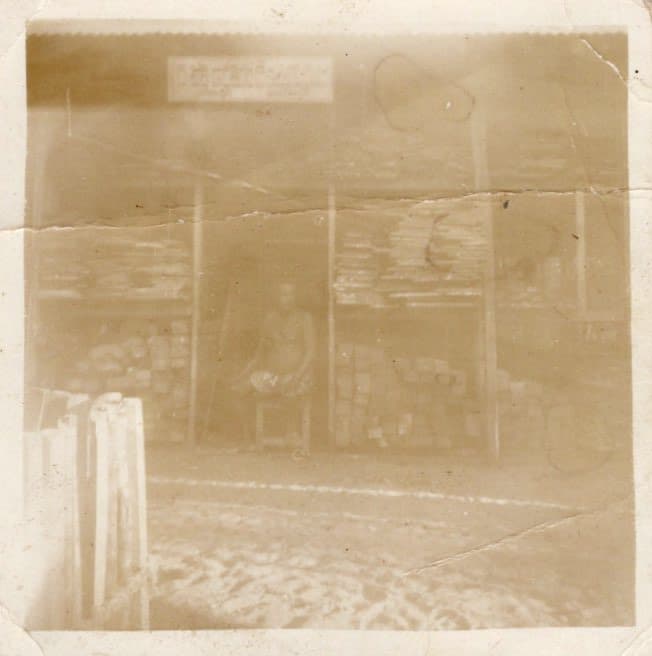 Sepia photograph of the original St. Xavier Timber shopfront, with sawn timber stacked to the rafters and a man seated at the counter.