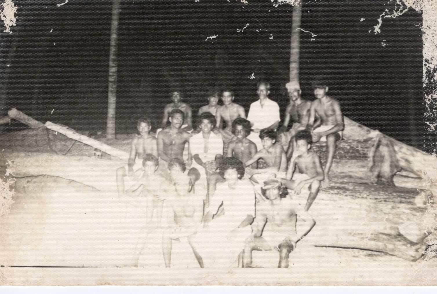 A large group of yard workers posed together on and around a felled log at the timber yard.