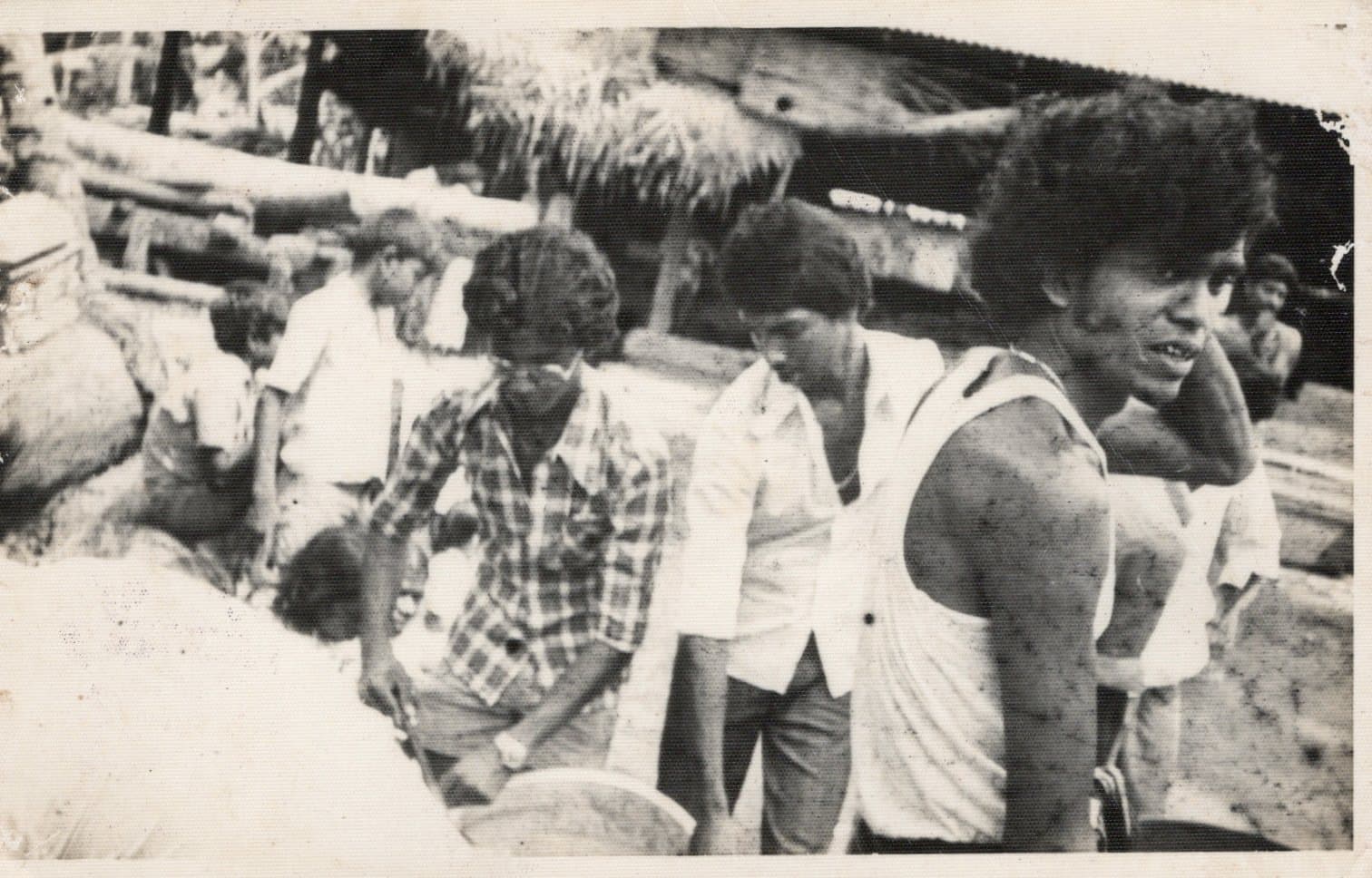 Yard workers at work in the timber store, with sawn timber and the mill shed behind them.